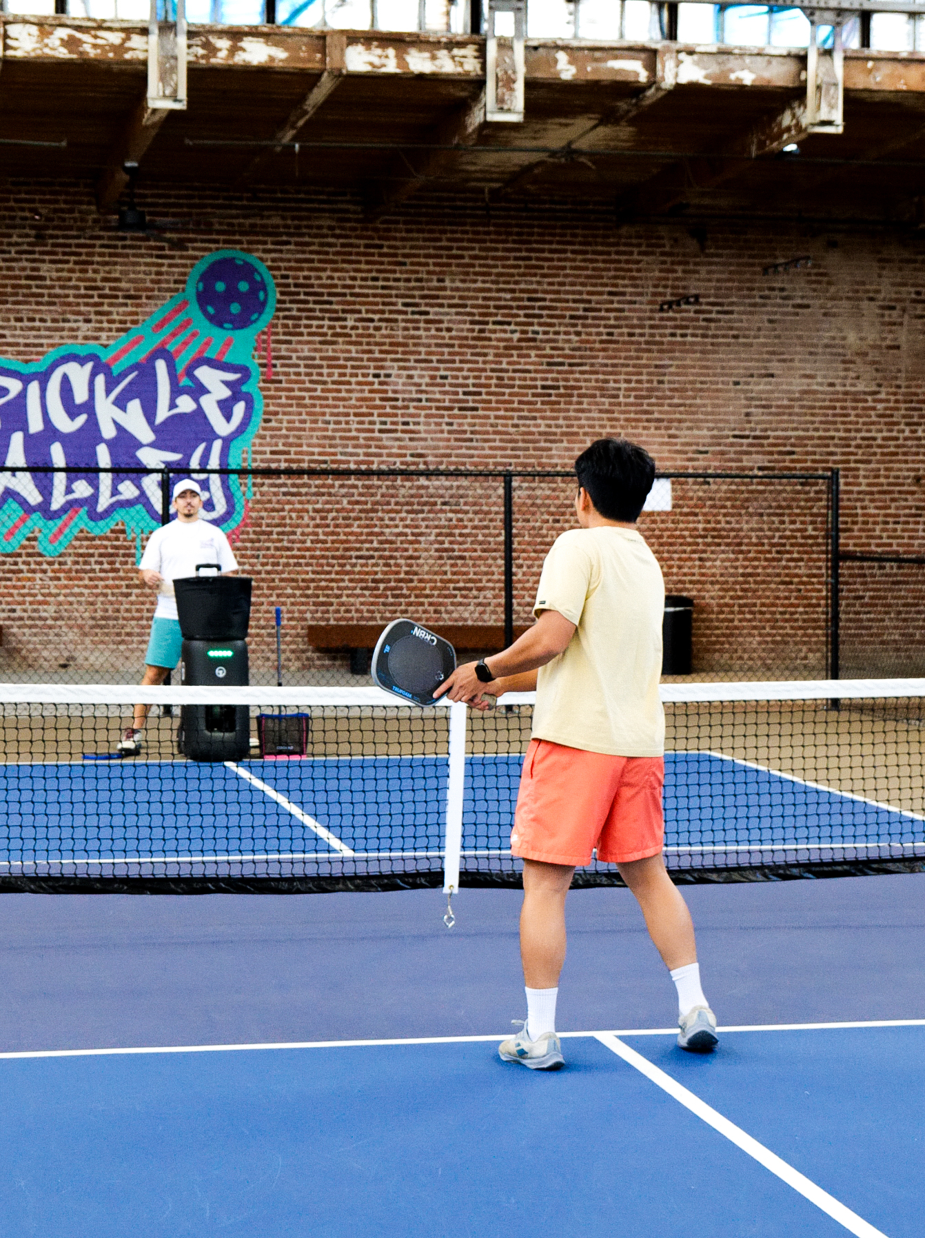 Player practicing with the ball machine at Pickle Alley